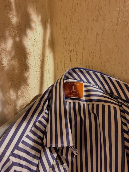 A bold navy and white striped cotton shirt. The close-up shows our brand label, a sign of handcrafted quality in every garment we make.
