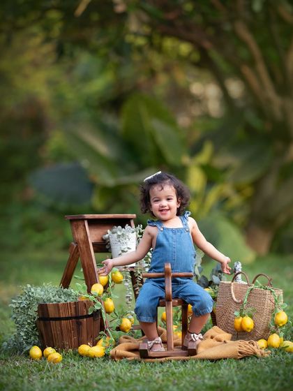 When life gives you lemons, have a photoshoot! This little one is having a blast with our lemon-themed setup, complete with a tiny wooden rocking horse.