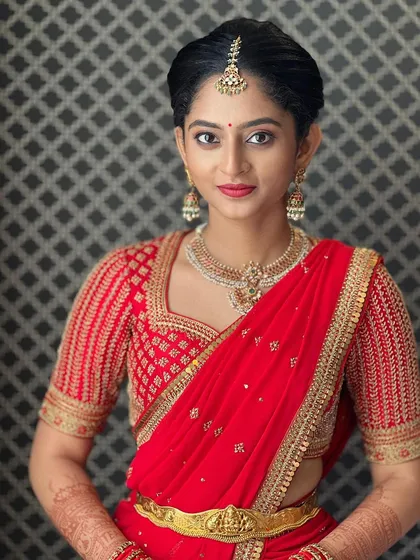 Resplendent in red, Manya wears a custom pure georgette dupatta with a hand-embroidered border. It is paired with a silk blouse featuring intricate hand embroidery for a complete, regal look.
