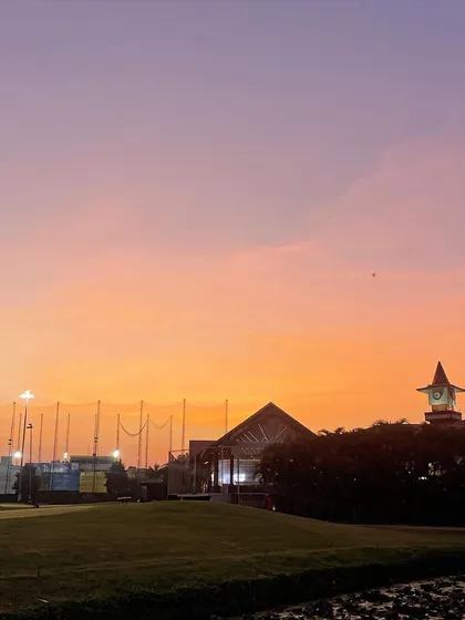 The sky glows with color over the driving range at dusk. My coaching sessions can be scheduled for various times, including evening practice under the lights.