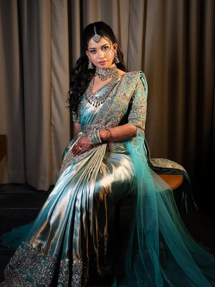 A bride in a stunning turquoise and silver saree gown. This modern silhouette is perfect for a reception or cocktail party, showcasing our design versatility.