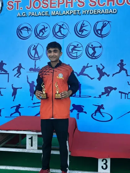 Yuv Vora proudly displays his two trophies on the podium at the St. Joseph's School national event. Each trophy is a symbol of countless hours of training and dedication.