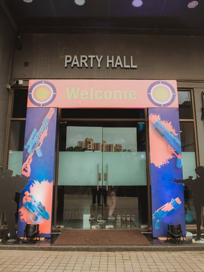 The entrance to the "Party Hall" for a Nerf Gun-themed event. The decor uses silhouettes of players and bright paint splatters to build excitement for the battle inside.