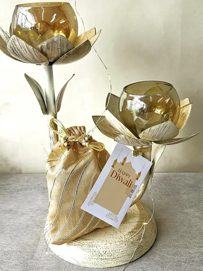 A unique lotus-shaped double T-light holder paired with a golden potli. This compact and elegant set is a wonderful gift for adding a touch of light and tradition to any home.