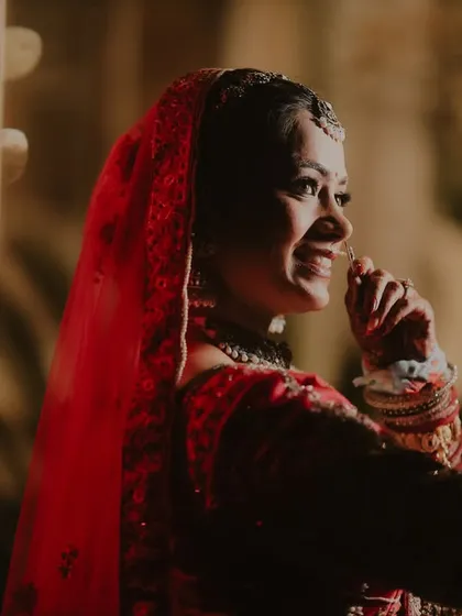 A candid, smiling portrait of the bride, Riya. The warm, side lighting creates a beautiful, intimate mood, capturing her genuine happiness.