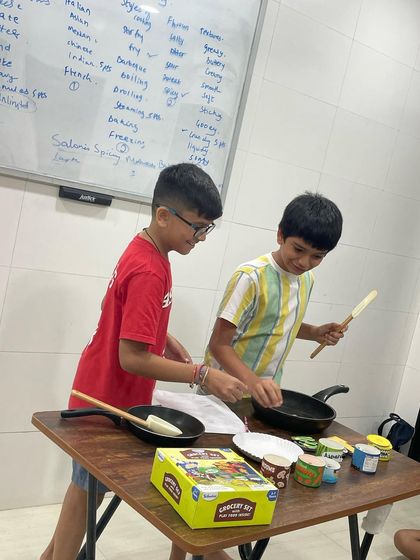 Older students get in on the fun too! Here, they are using the pretend cooking setup to practice more complex vocabulary and conversational exchanges, all while having a great time.