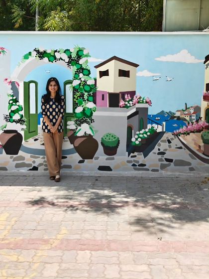 Posing with the right side of the streetscape mural, which features charming houses and greenery.
