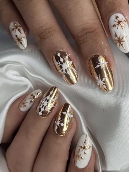 A luxurious white and gold Christmas theme. This set features high-shine gold chrome nails and matte white nails, both adorned with intricate snowflake and star designs.