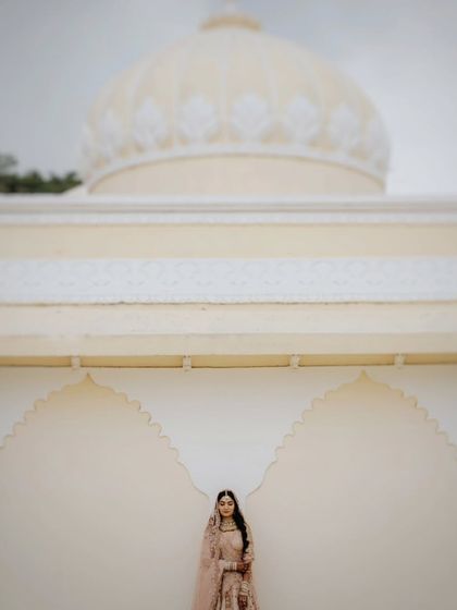 A minimalist bridal portrait, with the bride standing against a grand, white architectural backdrop, creating a sense of scale and elegance.