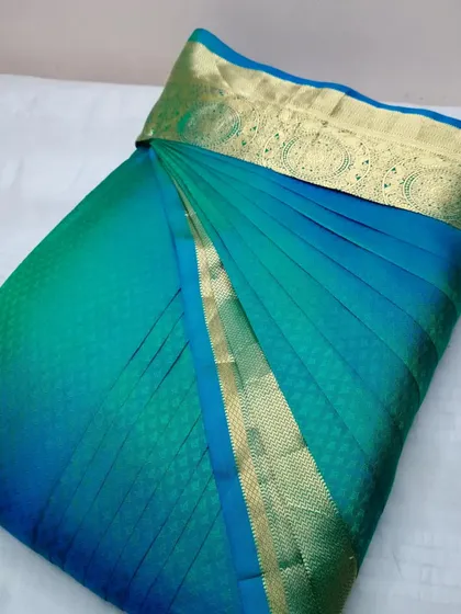 A teal and gold silk saree, pleated and ready to wear.