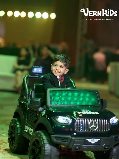 The joy of celebrating in a special outfit. This little boy looks dapper and happy in his custom tuxedo and bow tie, enjoying his birthday party from his favorite ride.