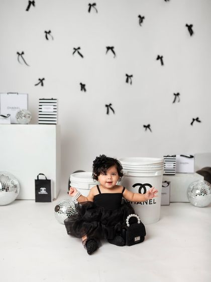 The little one sits happily among the props, looking absolutely adorable in her black tutu and accessories.