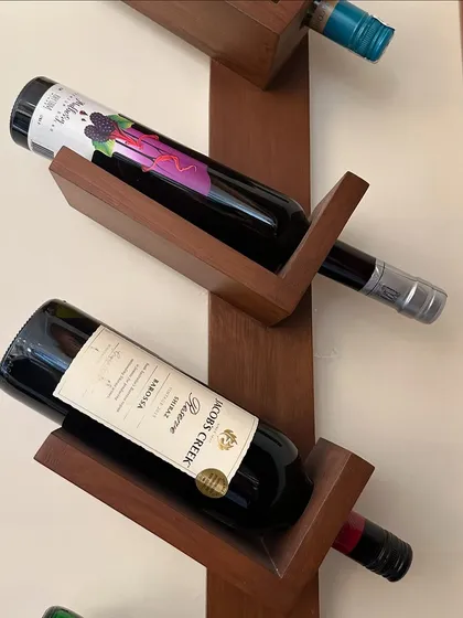 A detail shot of the custom wall-mounted wine rack, crafted from wood. Its modern, angular design turns wine storage into a decorative feature, adding to the bar area's sophisticated look.