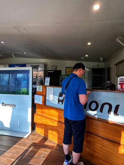 The hub of our camp. A golfer checks in at the Pro Shop reception desk, with our digital information kiosk and PXG display visible in the background.