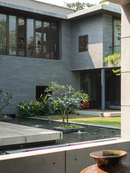 A serene water body wraps around the living spaces, reflecting the building and the sky, and creating a cool microclimate.