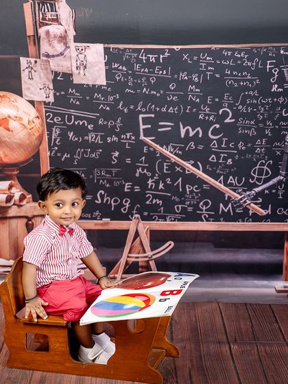 From ABCs to E=mc², this little scholar is top of the class. Dressed in a school uniform, he's ready to learn at his tiny desk in front of a chalkboard full of complex formulas.