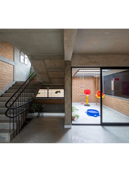 The interior staircase and a view into a semi-outdoor play area. The design ensures that even circulation spaces are well-lit and visually connected to other parts of the school.