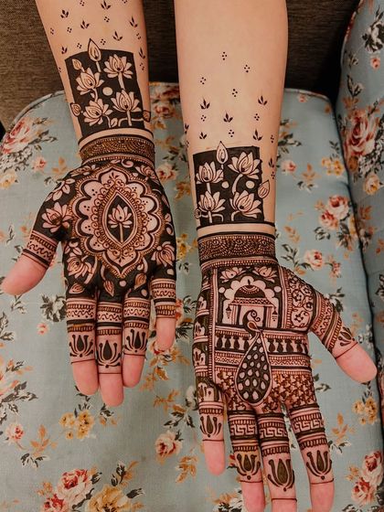 This design combines a central lotus mandala on one hand with a pictorial scene on the other, featuring a peacock and a domed structure. The lotus block pattern on the wrist is a modern touch.