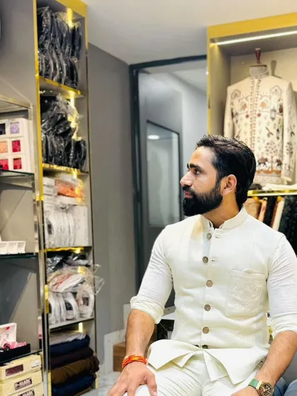 A candid moment in my men's couture section. I am surrounded by fabric swatches and designer pieces, always ready to help you find or create the perfect outfit for your occasion.