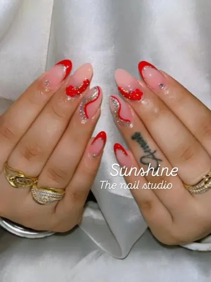 A classic red nail set for Karwa Chauth. The design includes red French tips, silver glitter swirls, and rhinestone accents for a touch of festive glamour.