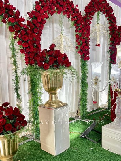 A classic and opulent Valima stage in red and gold. The decor features dramatic red rose arches, elegant candelabras, and gold vases, creating a timeless and regal setting for the couple.