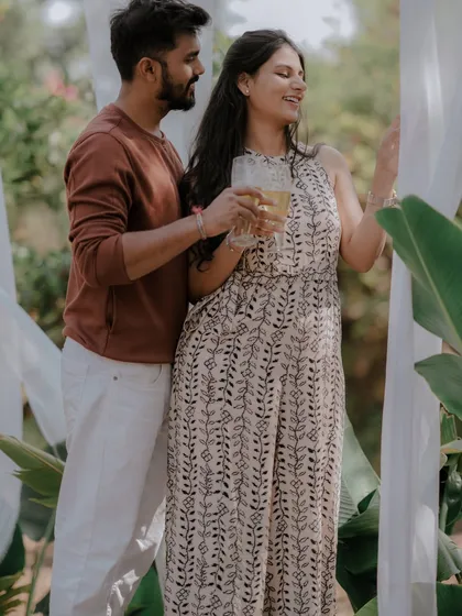 A celebratory toast to their future together. This shot captures a simple, happy moment during a relaxed outdoor pre-wedding session, framed by soft white drapes.