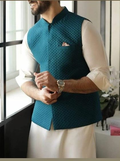A teal quilted Nehru jacket paired with a white kurta. This is a stylish and comfortable option for festive gatherings or casual events.