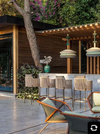 The outdoor bar and lounge area, featuring a stone bar under a wooden trellis. This space is an entertainer's dream, seamlessly connected to the adjacent indoor gym.