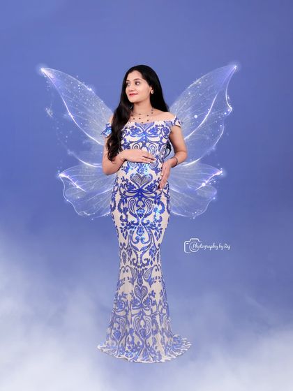 A magical studio portrait with edited-in fairy wings. The mother-to-be wears a stunning blue and white sequined gown.