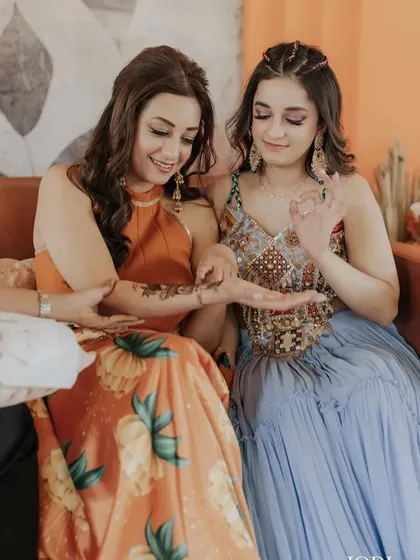 A candid moment during the Mehendi ceremony. The client's wavy hair is casually pinned back, looking effortlessly chic.