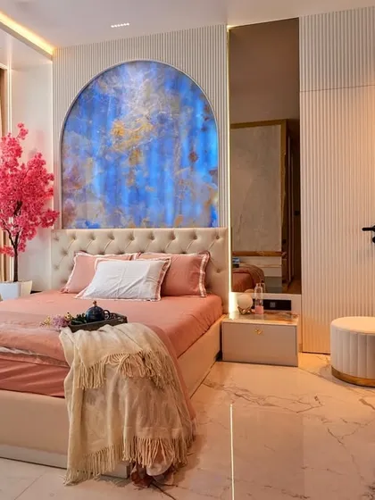 For this young client's bedroom, we created a sanctuary that reflects her personality. The design centers around a stunning blue stone arch, complemented by soft peach and white tones, while the deep blue fluted wardrobes add a touch of modern sophistication.