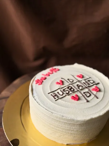 A side view of the "best husband" tic-tac-toe cake, showing the clean buttercream finish.