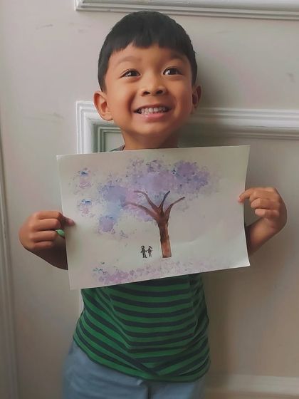 A very happy young artist with his completed cherry blossom tree painting, showcasing his unique take on the subject.