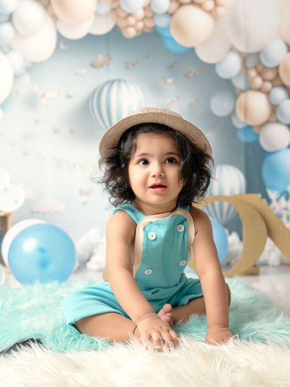 A dreamy blue and white balloon setup for a special first birthday. This little boy in his hat and overalls looks so adorable in his sky-themed celebration.