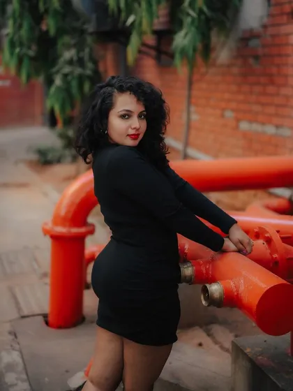A duplicate of image 139, this portrait uses the contrast of a black dress against red pipes for a strong, industrial-chic photo.