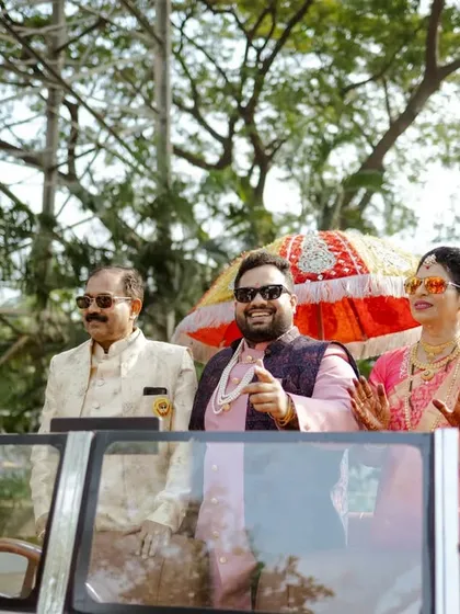 The couple enjoying their ride in the vintage car, waving to their loved ones. A happy and stylish moment.