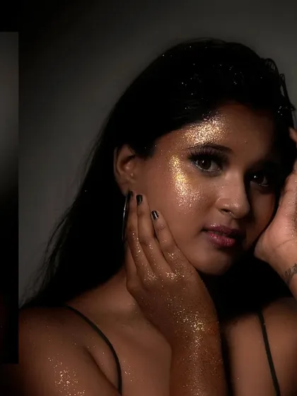 A close-up portrait where the model is covered in gold glitter, creating a magical, stardust effect that glows in the light.