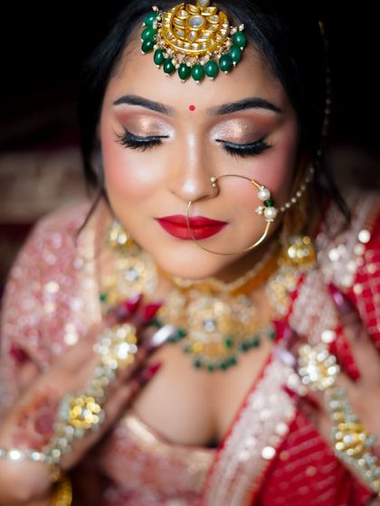 A close-up of a classic red-lip bridal look, showcasing flawless skin and shimmering gold eyeshadow.
