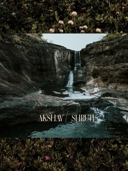A wide, cinematic shot of a couple at the base of a waterfall, capturing the grandeur of the location.