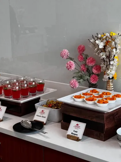 A clean and modern dessert and beverage station. This setup includes our Berry Lemonade mocktails, Hawaiian Salad, and fresh mangoes, all clearly labeled for guests.