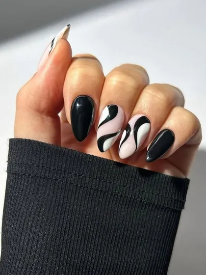 For a bold and graphic statement, this black and white abstract swirl design is a favorite. The high contrast and fluid lines on a nude base create a sophisticated and modern manicure.