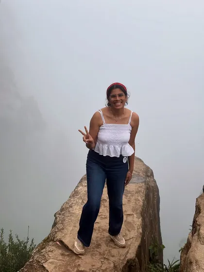 A happy trekker making a peace sign at a viewpoint in Kodaikanal, with the valley covered in a thick blanket of fog.