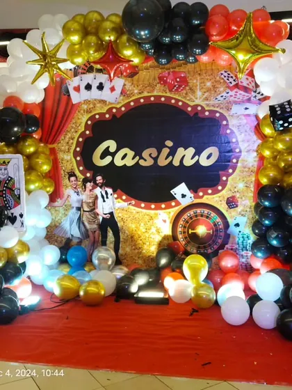 We love bringing creative and fun adult party themes to life, like this vibrant Casino night. The decor includes a custom glittery backdrop, balloon arrangements in red, black, and gold, and themed props like playing cards and dice.