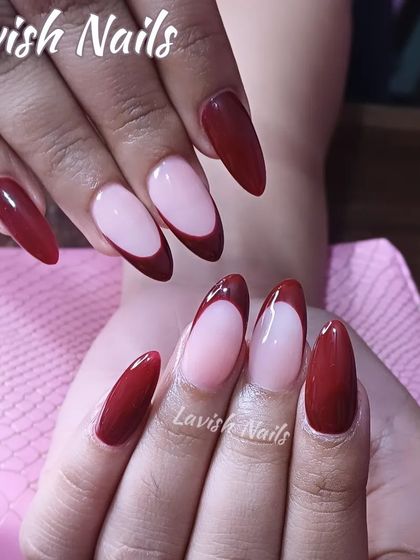 A sophisticated and deep red French tip on long almond nails, offering a dramatic twist on the classic.