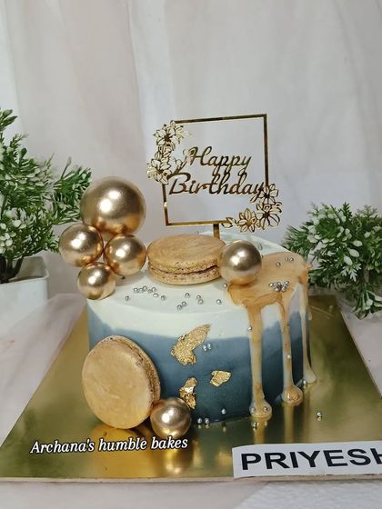 A stylish drip cake with macarons and golden spheres for Priyesh's birthday.