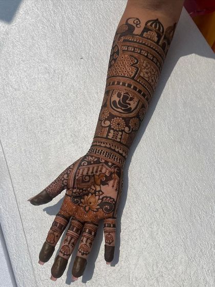 A single-hand view of a detailed bridal design, featuring Ganesha, peacocks, and domes.