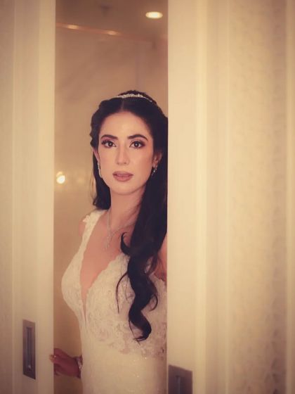 A bride in a white gown peeks out from behind a sliding door, a simple yet elegant portrait.