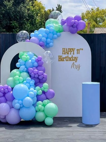 A cool and refreshing outdoor setup for an 11th birthday. I used a white arch backdrop and a balloon arrangement in shades of blue, purple, and mint green.