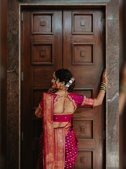 A full view of this bride's stunning look, showcasing her intricate blouse design and a beautiful floral hair arrangement that complements her traditional Marathi saree.