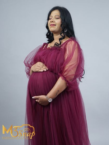 A serene and peaceful moment captured in the studio. The mother-to-be's calm expression and gentle hold on her belly convey a sense of quiet joy.